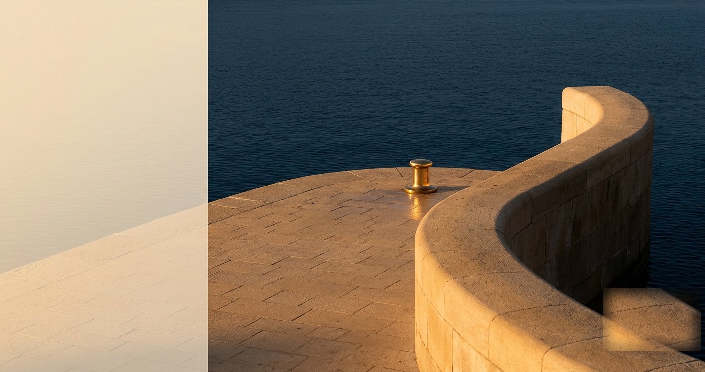 Curved harbour wall with a brass mooring post at golden hour, calm navy sea beyond